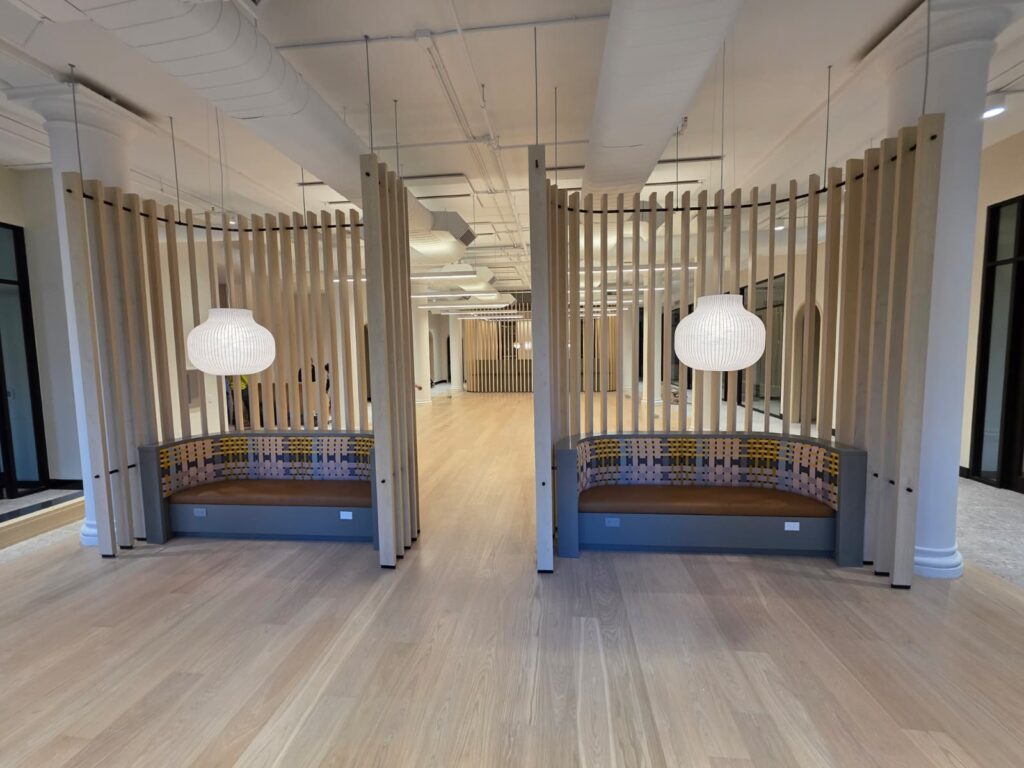 Custom curved banquette with vertical wood slats and pendant lighting, fabricated by First Class MasterCraft for a financial office in NYC.