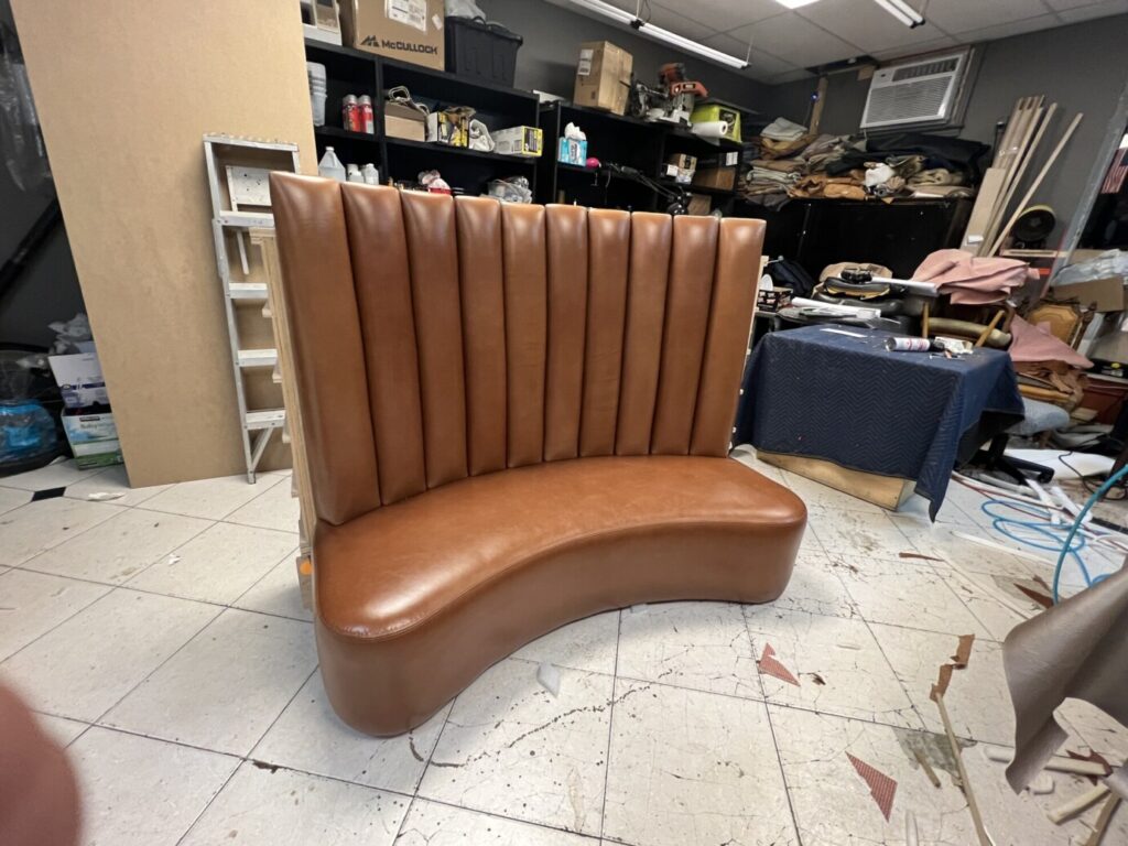 Curved high‑back custom banquette upholstered in brown leather, fabricated by First Class MasterCraft for a luxury jewelry store.