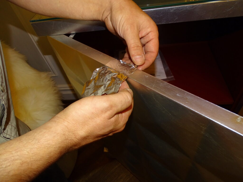 Technician repairing the silver leaf on a Barbara Barry for Baker Diamond Chest in the client’s home before restoration.