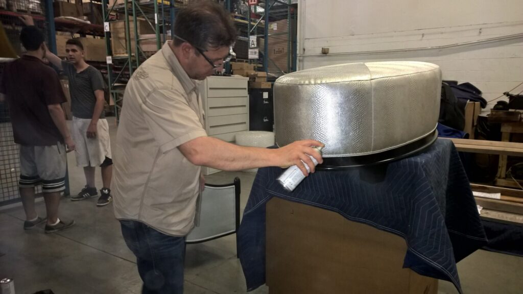 Barbara Barry for Baker Oval X ottoman in the workshop with a technician working on the repair process.