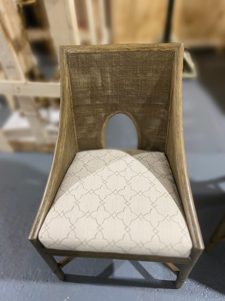 Bamboo dining chair with a woven oval‑cutout backrest and patterned upholstered seat.