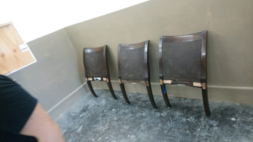 McGuire cane dining chairs in the finishing room before restoration, prepped for spraying and finishing work.