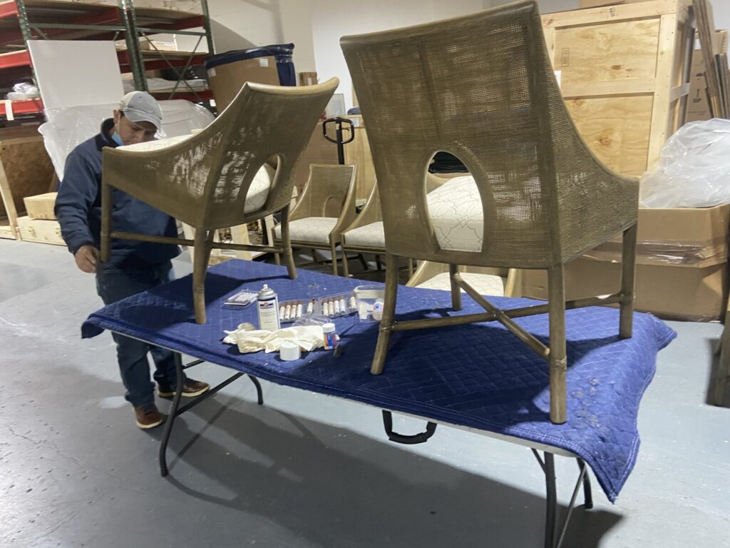 Technician performing on‑site touch‑up work on McGuire cane dining chairs in the customer’s home.