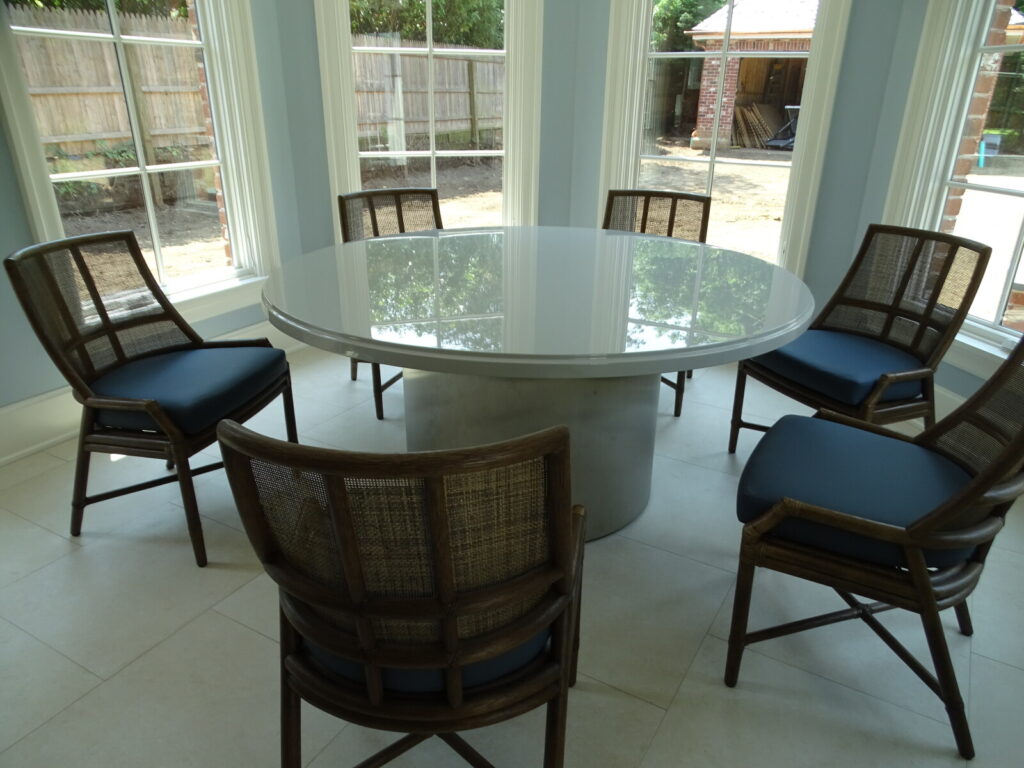 McGuire dining table with woven‑back chairs in a bright windowed interior.