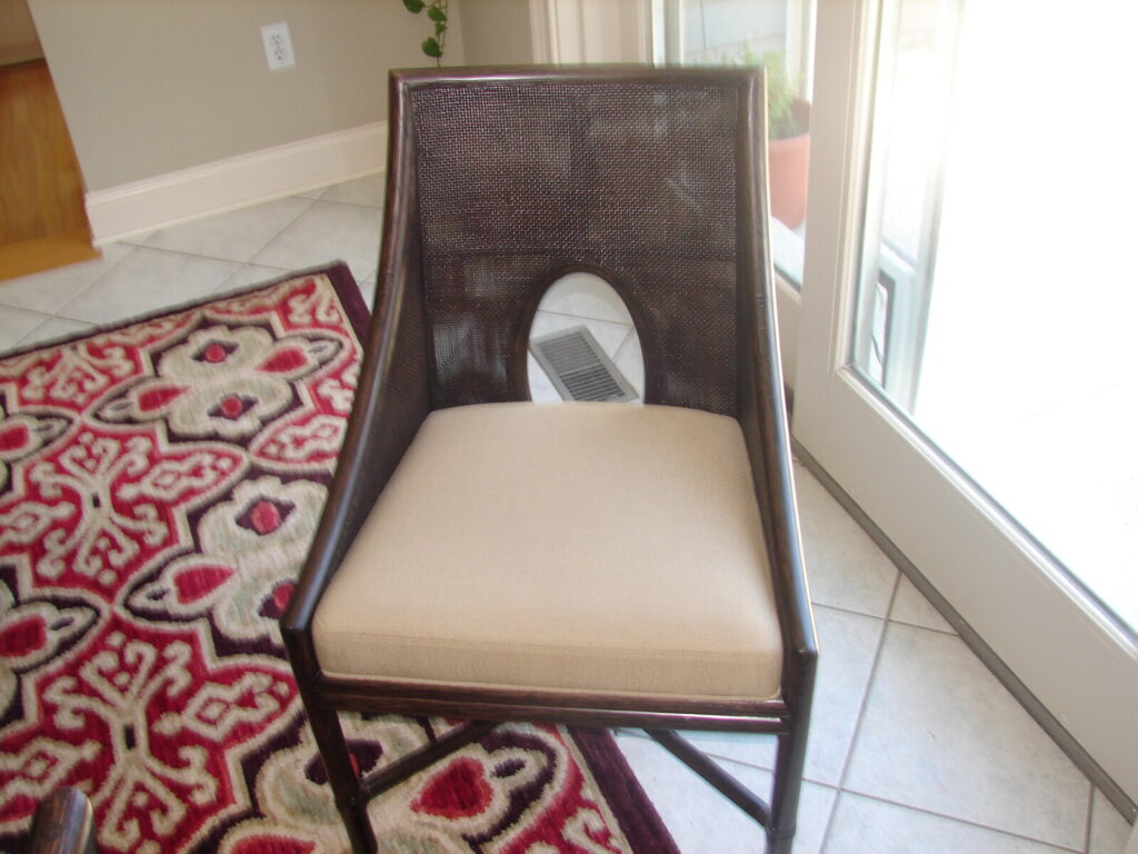bamboo dining chair with a cane oval‑cutout backrest and light upholstered seat.
