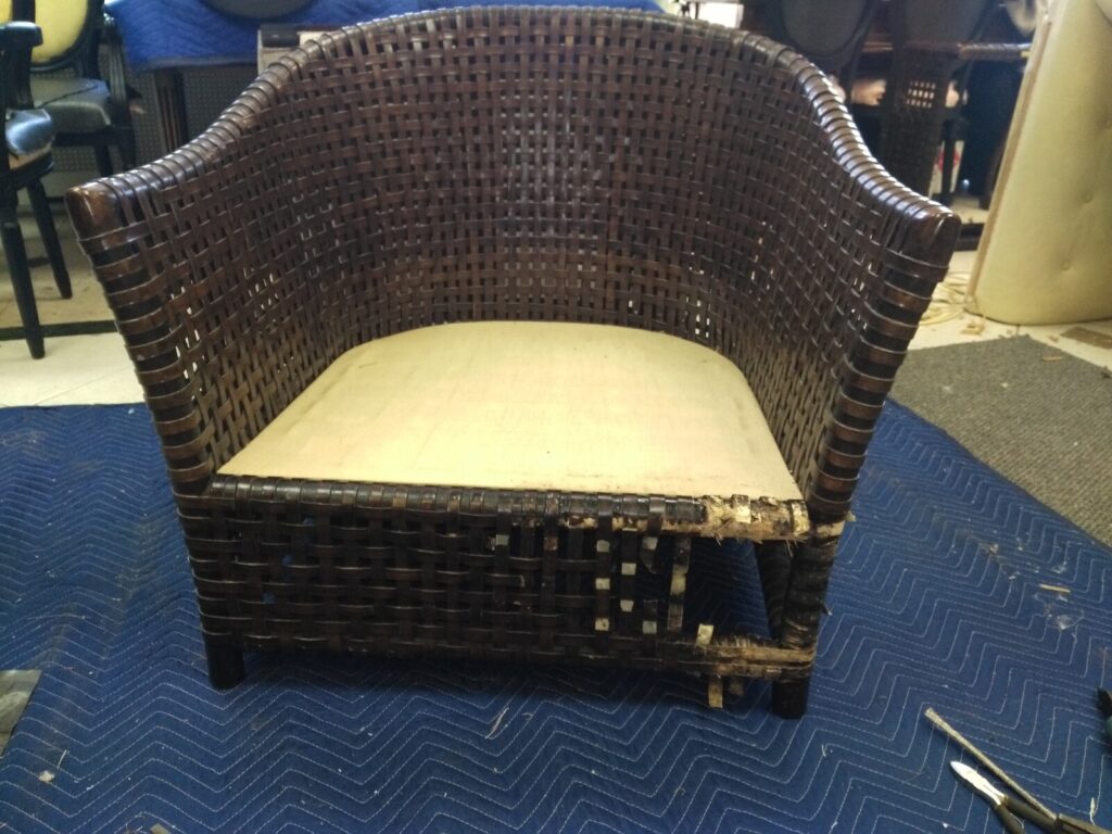 McGuire outdoor lounge chair before restoration showing worn woven‑resin rawhide detail in NYC, documented by First Class MasterCraft.