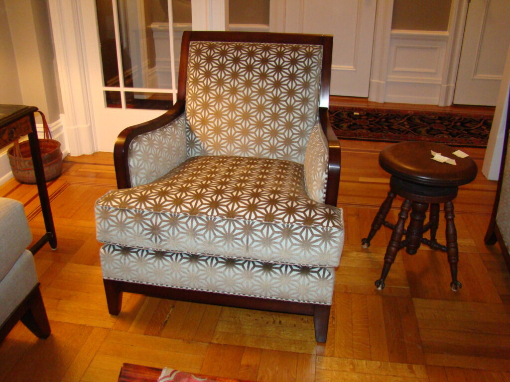 “Patterned armchair with a geometric starburst upholstery design and wooden frame, shown in a furnished interior space.