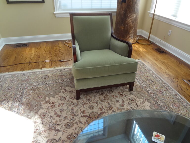 Restored baker upholstered armchair featuring a signature curved wingback silhouette and premium sage green ribbed velvet fabric, shown after delivery in a luxury residential setting.