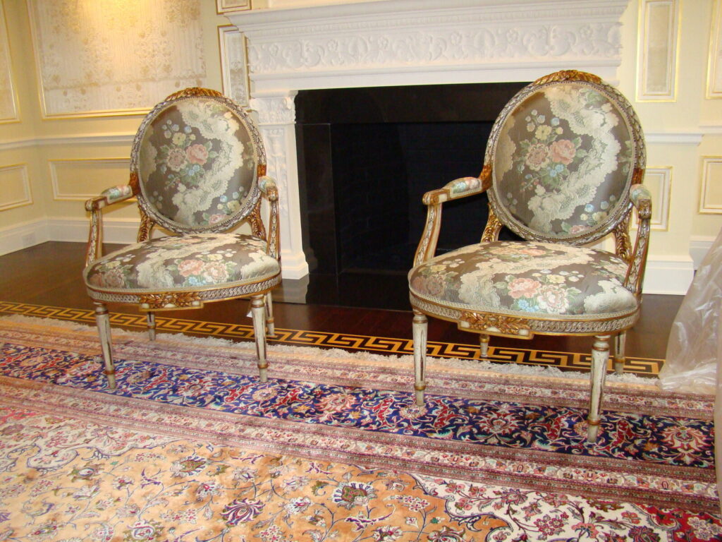 Pair of Baker Louis XVI–style gilded armchairs with tapestry upholstery shown after delivery.