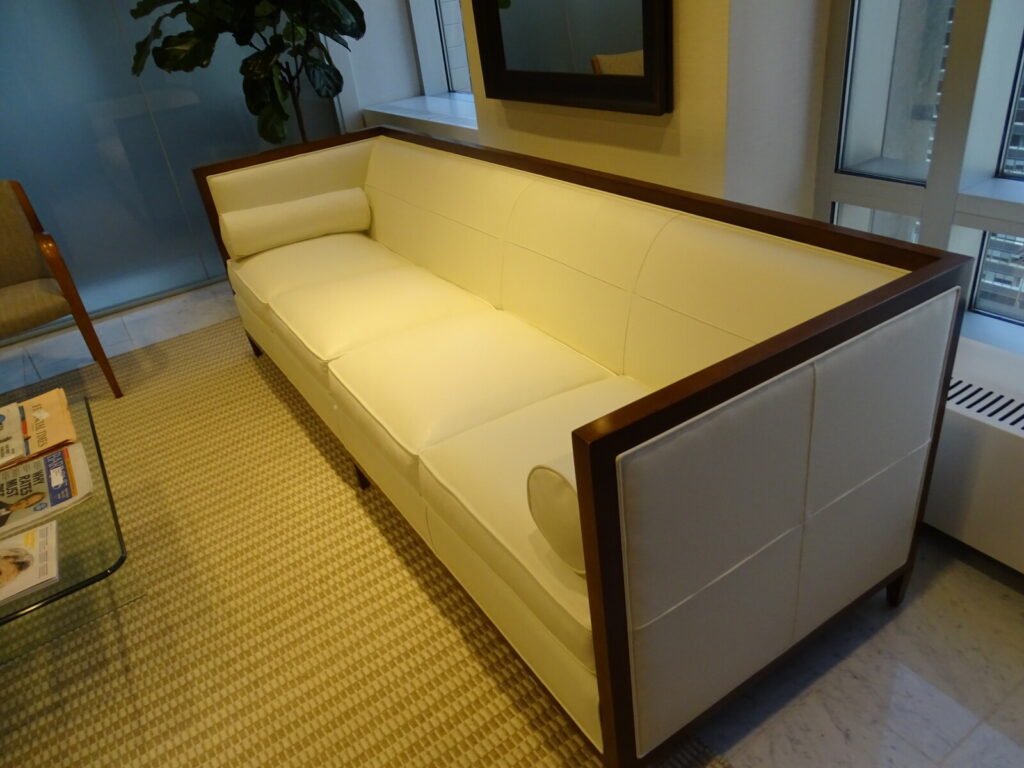 Restored Baker leather sofa featuring a modern tuxedo silhouette seam on the interior back and arms, upholstered in premium white leather with a dark wood frame.