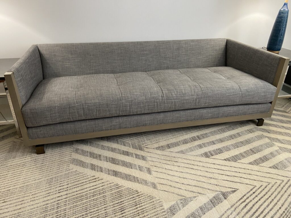 Restored Baker tuxedo-style sofa featuring custom premium white leather upholstery with precision top-stitched paneling, matching leather bolster pillows, and a dark mahogany wood frame.