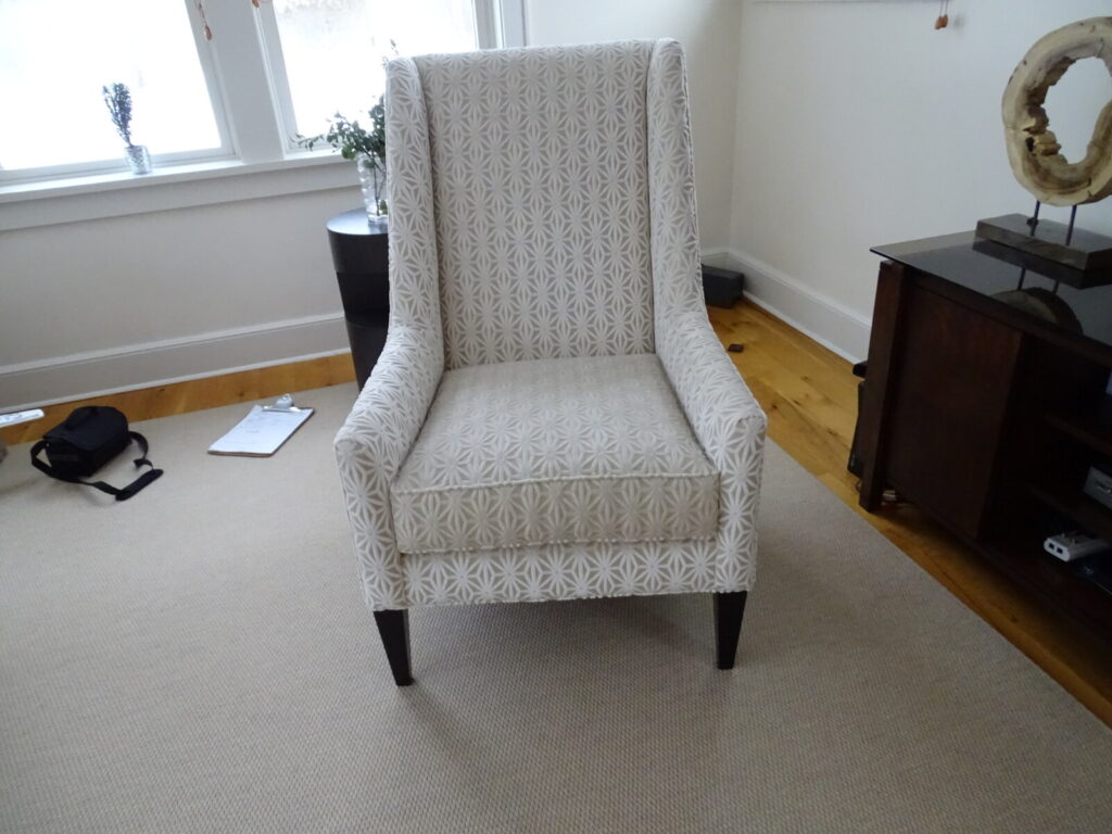 High‑back patterned armchair with geometric upholstery and tapered legs, placed in a well‑lit residential living space.