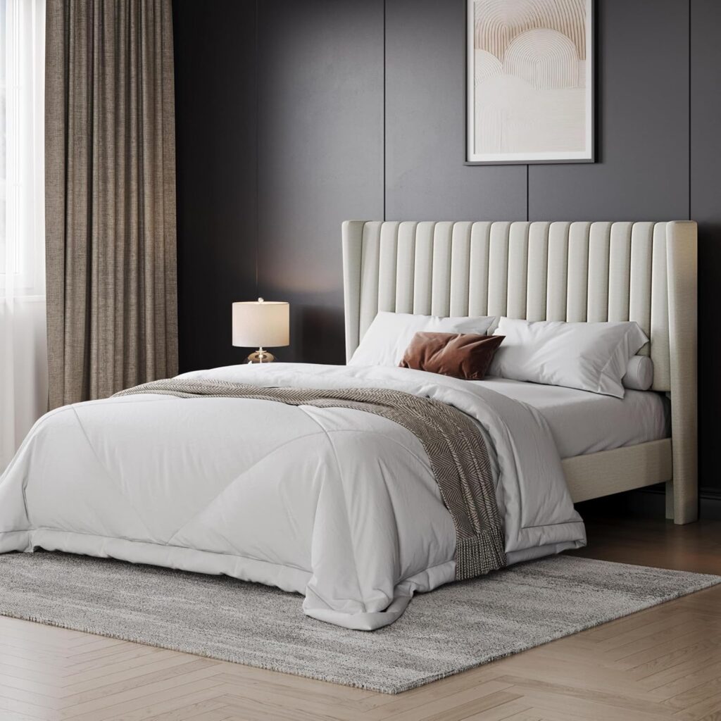 Modern bedroom with a tall upholstered headboard, neatly made bed, nightstand lamp, and dark wall panels.