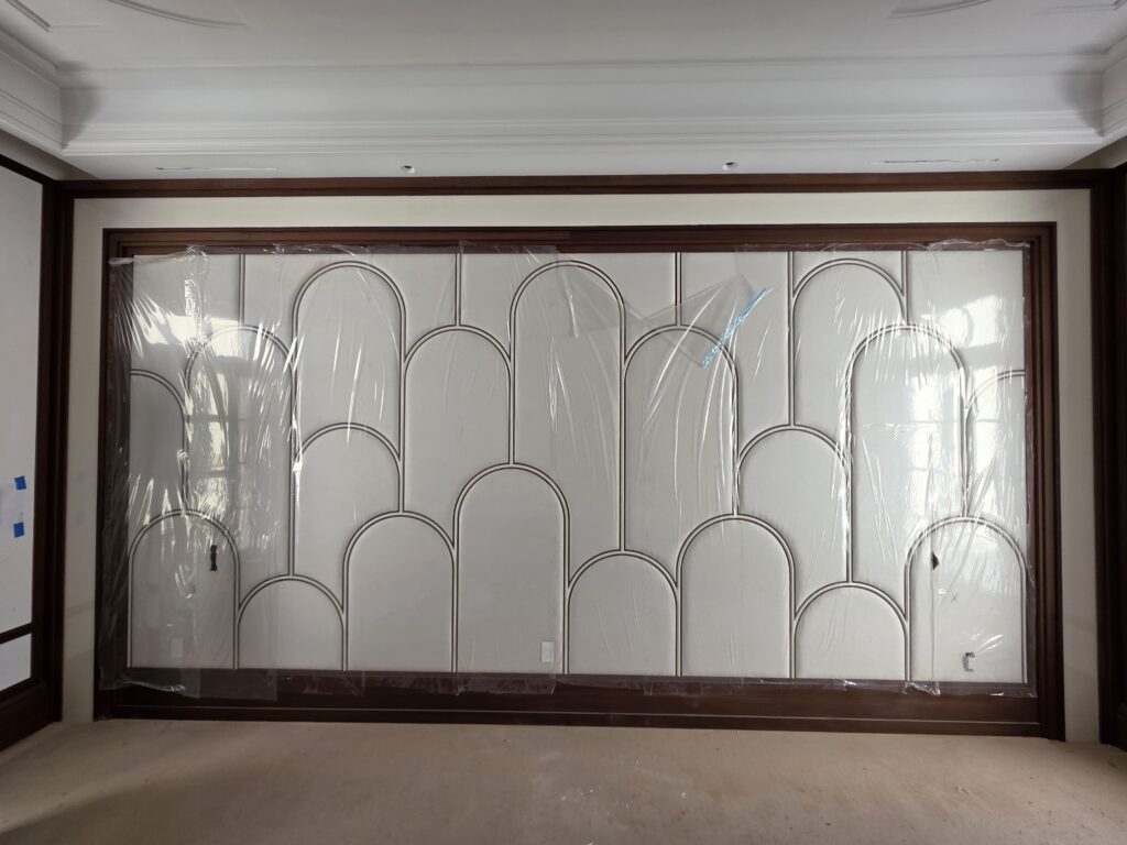Decorative wall panel with repeating arched shapes, dark trim, protective plastic covering, and integrated outlets along the bottom edge.