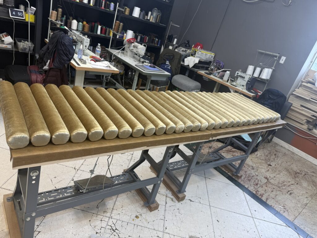Window-seat banquette in the shop with roll cushions placed for fitting.