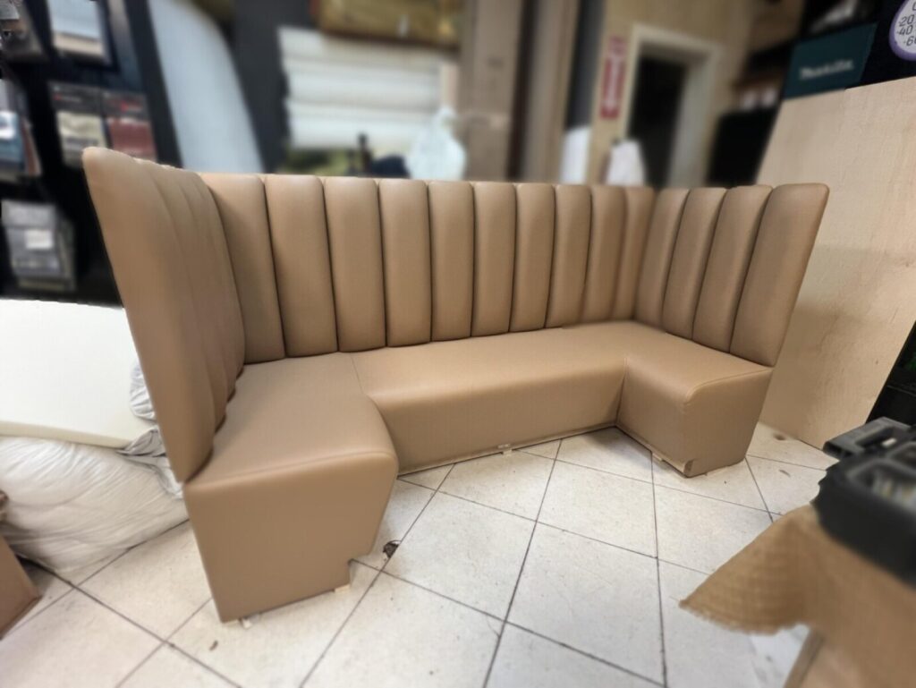 Channel-back banquette with vertical panels and tight upholstered seat.