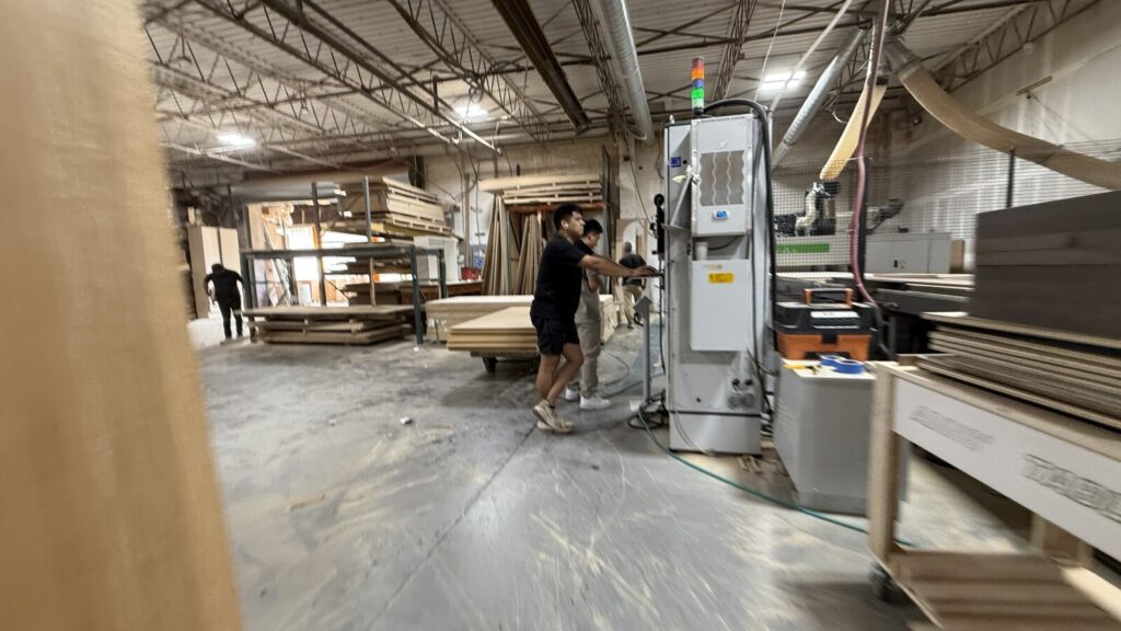High-tech furniture fabrication showing a CNC machine cutting structural components for bespoke sofa frames.