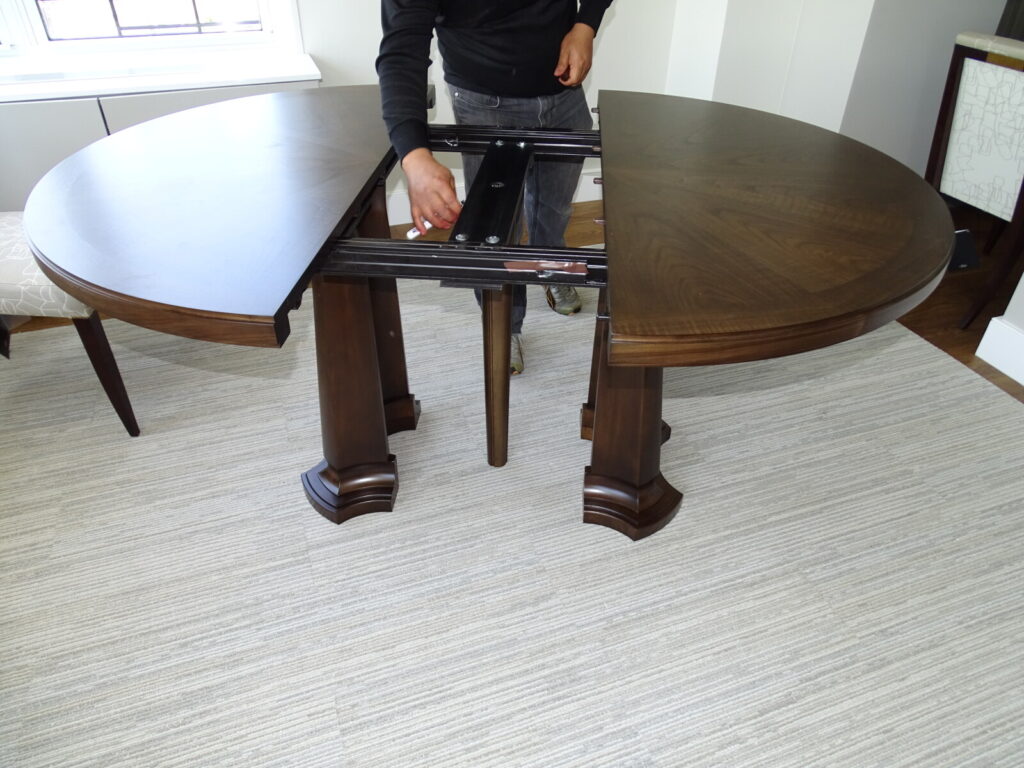 Adjusting the extension tracks on a dining table in the client’s home during on‑site repair.