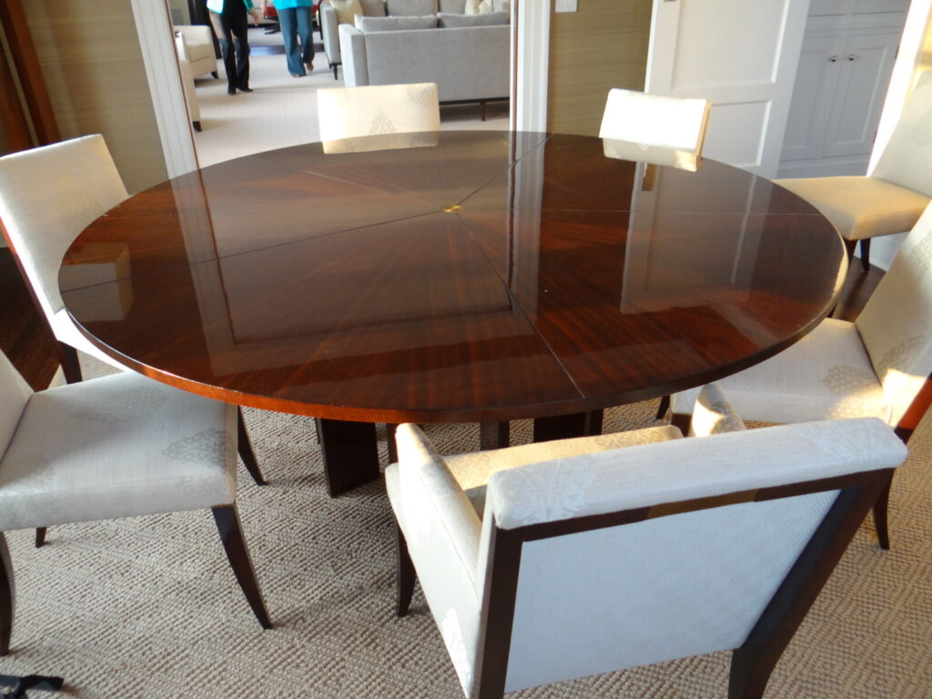 Refinished Baker Stately Homes Jupe table photographed in the client’s home, showing a high‑gloss radial mahogany top in a beautifully styled room.