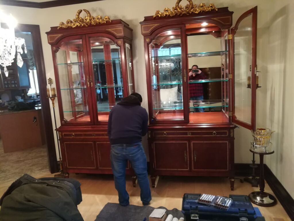 Baker Stately Homes breakfront display cabinet receiving final detailing during restoration.