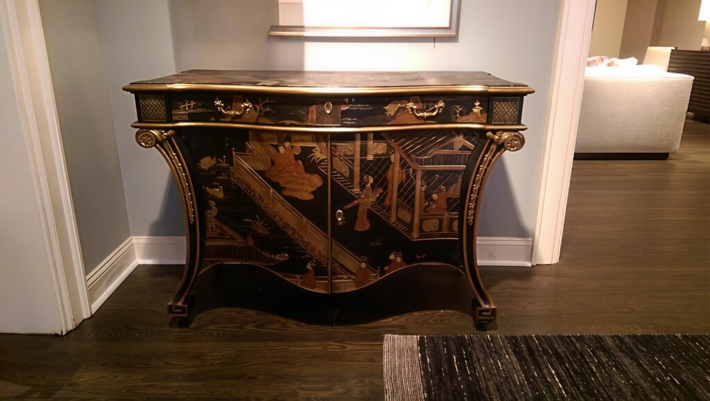 Chinoiserie black lacquer commode restored with detailed surface repair and refinishing, shown after delivery in a finished interior.