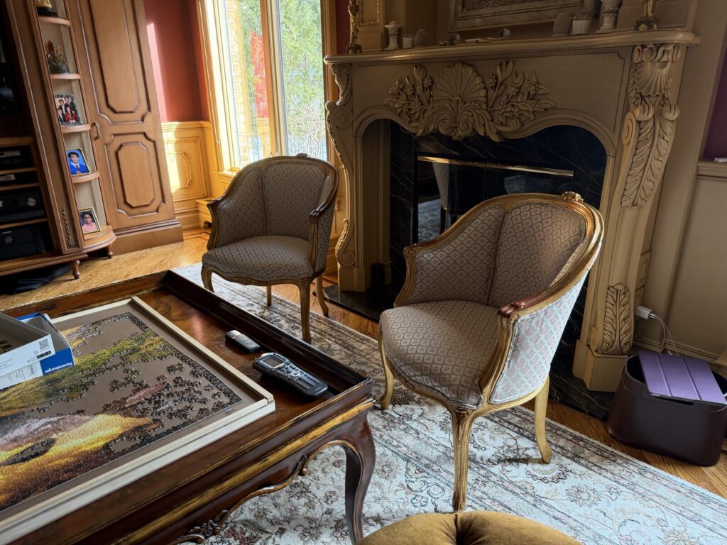 Pair of antique gold leaf chairs fully restored and reupholstered, shown after delivery in a finished interior.