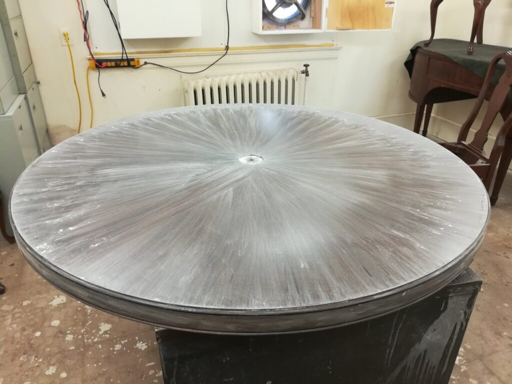 Sanded Baker Barbara Barry round mahogany dining table in the workshop, prepared for the final refinishing coat.