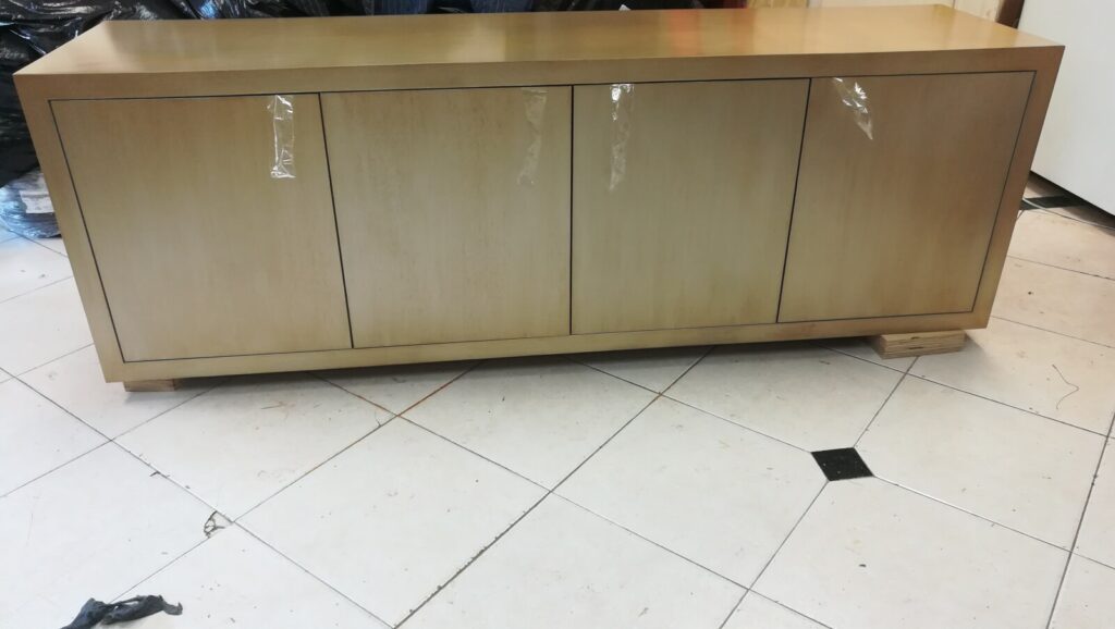 Refinished Baker sideboard in the workshop receiving final touch‑ups before delivery