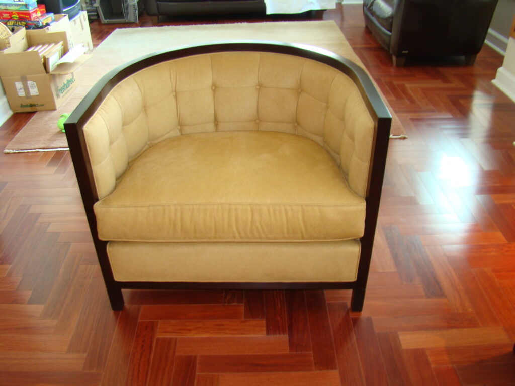 Tufted tub chair shown before refinishing and reupholstery, photographed in its original condition.