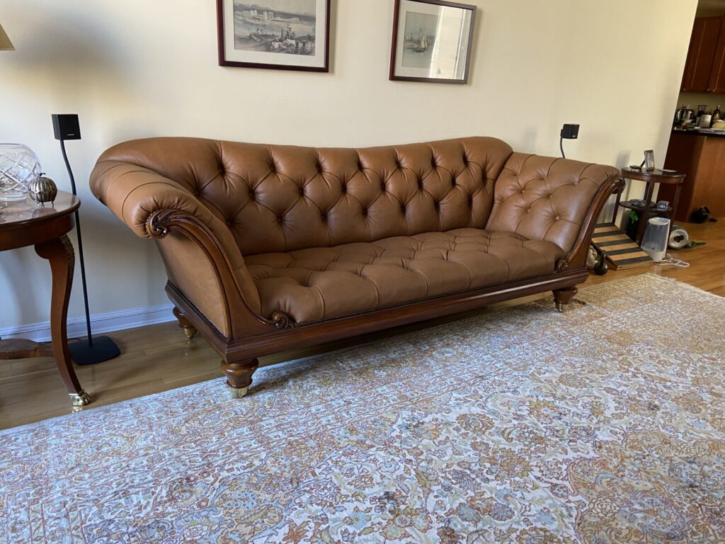 Brown leather tufted sofa fully refinished and reupholstered, shown after completion in a finished interior.