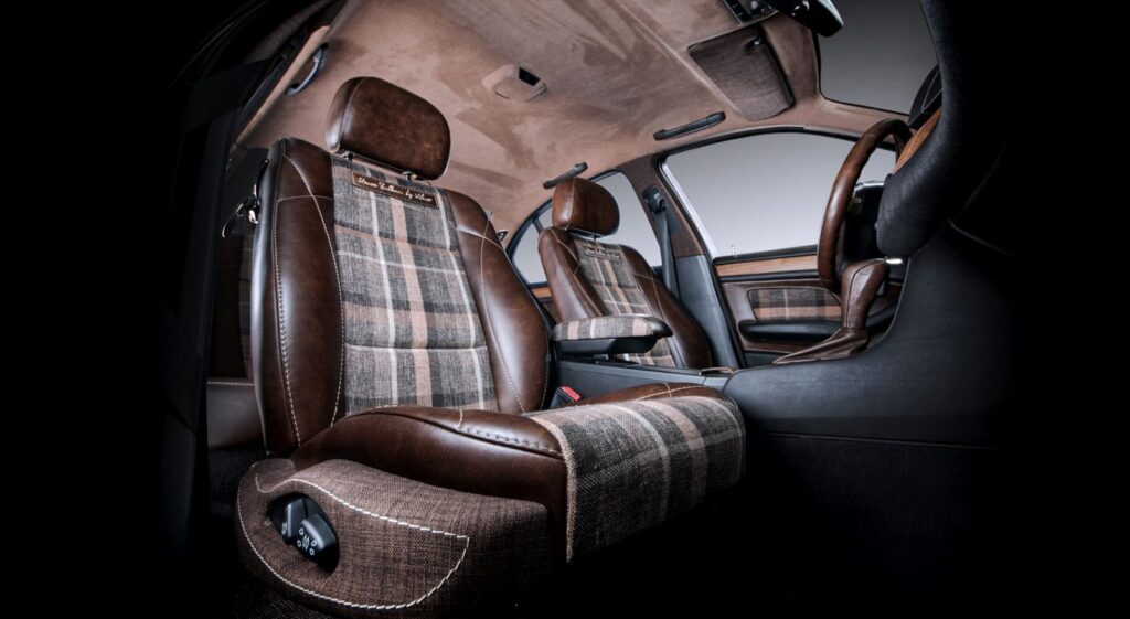 Luxury automotive interior featuring custom dark brown leather seats with sophisticated plaid fabric inserts and a matching suede headliner.