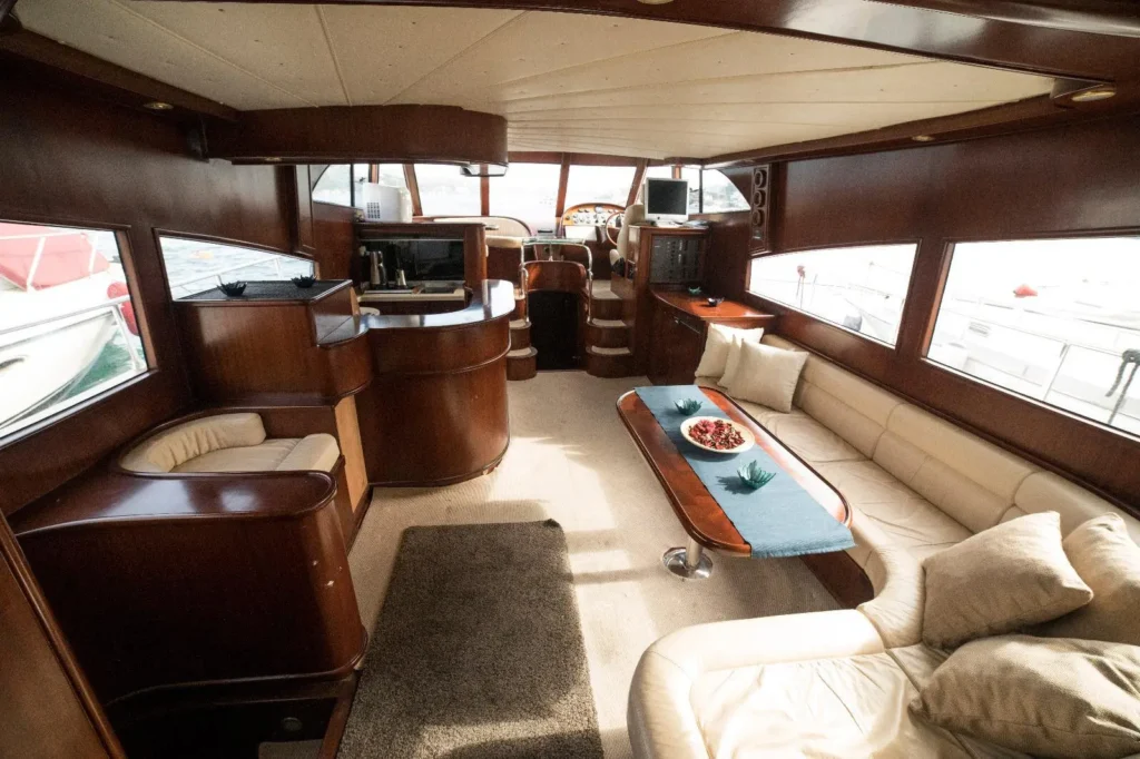 Classic luxury yacht salon with cream-colored custom leather sofa, wood-paneled walls, and bespoke cabinetry.