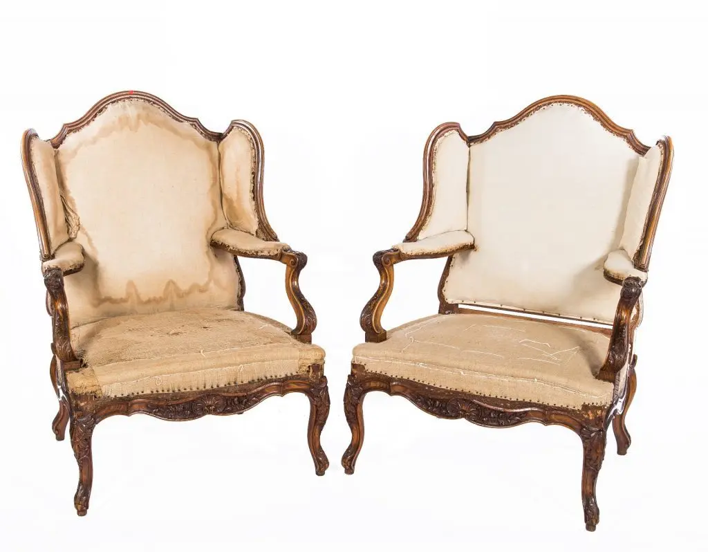 Two antique wooden chairs fully stripped to bare frames during the restoration process.