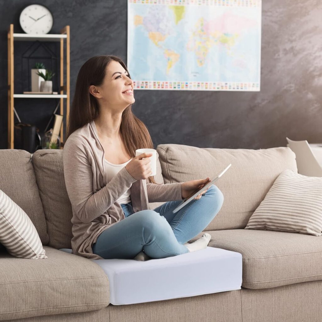 Woman sitting on a sofa testing a newly replaced cushion and smiling during the upholstery process.