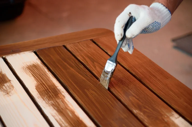 Applying the final coat of wood finish to a table during the refinishing process.