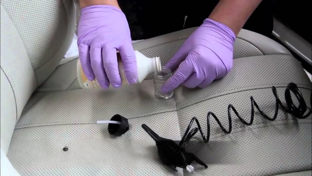 Technician preparing leather dye on a car seat before spraying it for restoration.