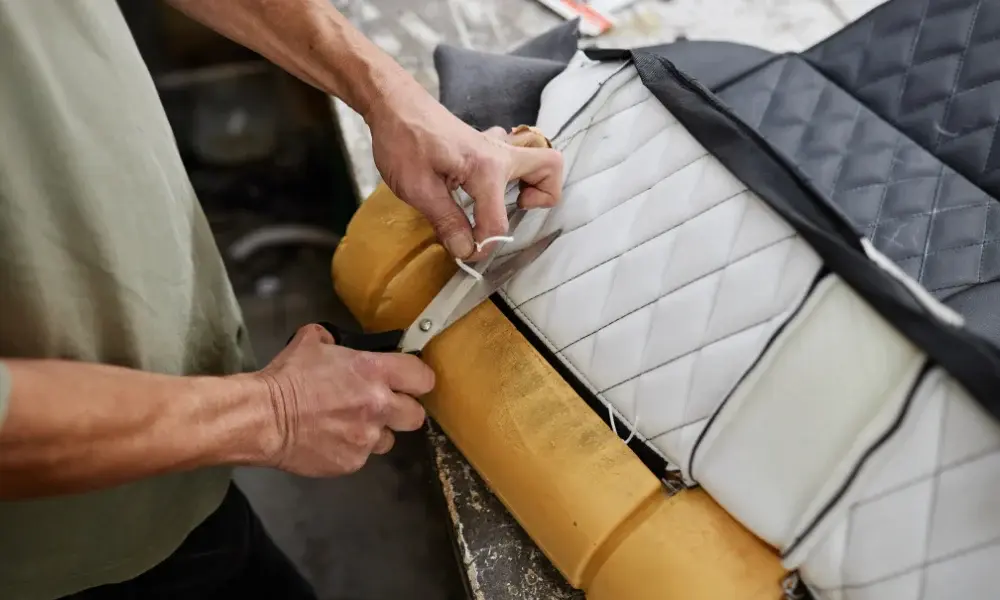 “closeup of a staple gun securing quilted fabric over foam padding