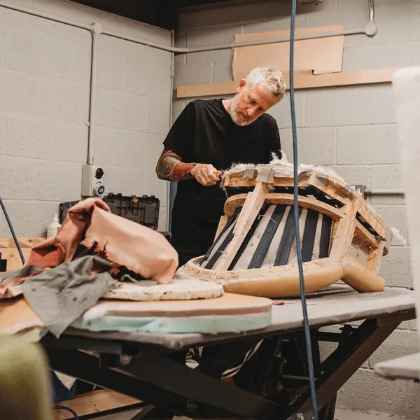 Craftsman working on a chair in the upholstery workshop during the restoration process.