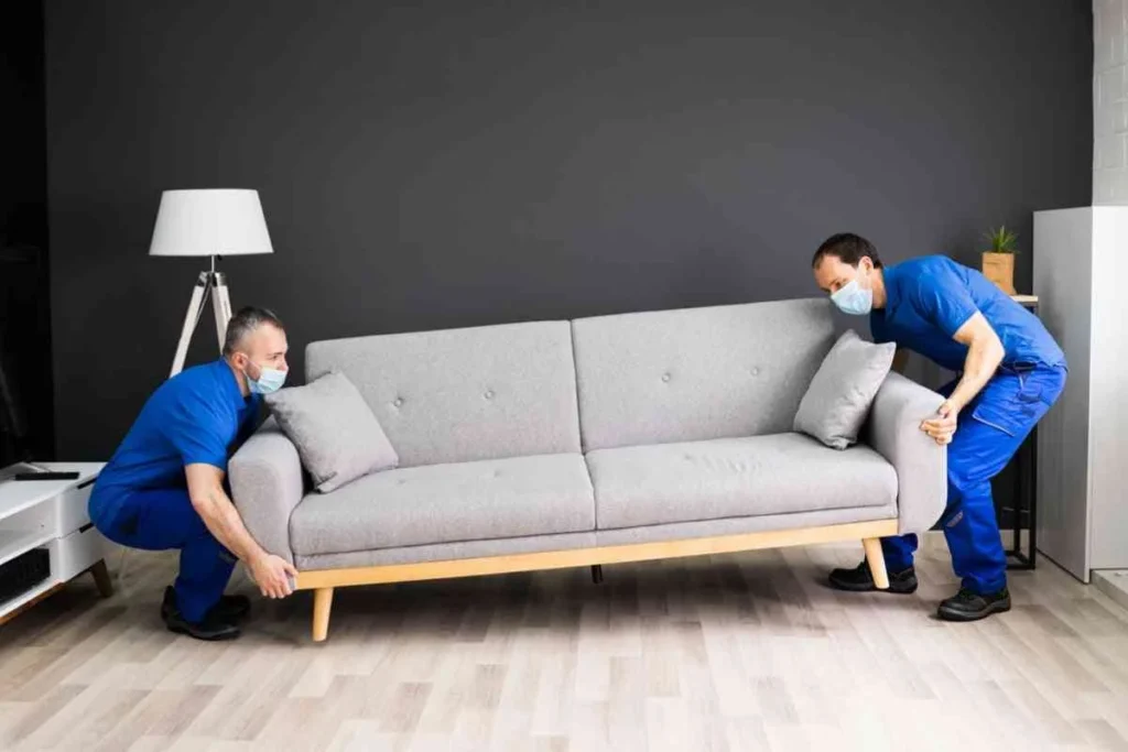 Two workers lifting a sofa during a white‑glove pickup process in the client’s home.