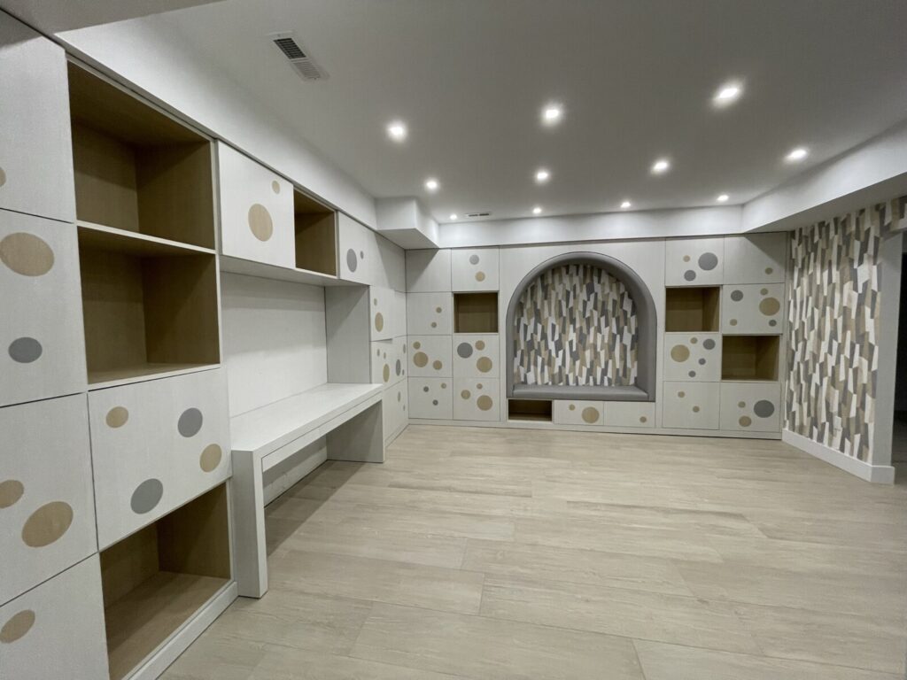 Custom bookcase wall system with integrated round banquette, photographed in the fully finished room from a right‑angle view.