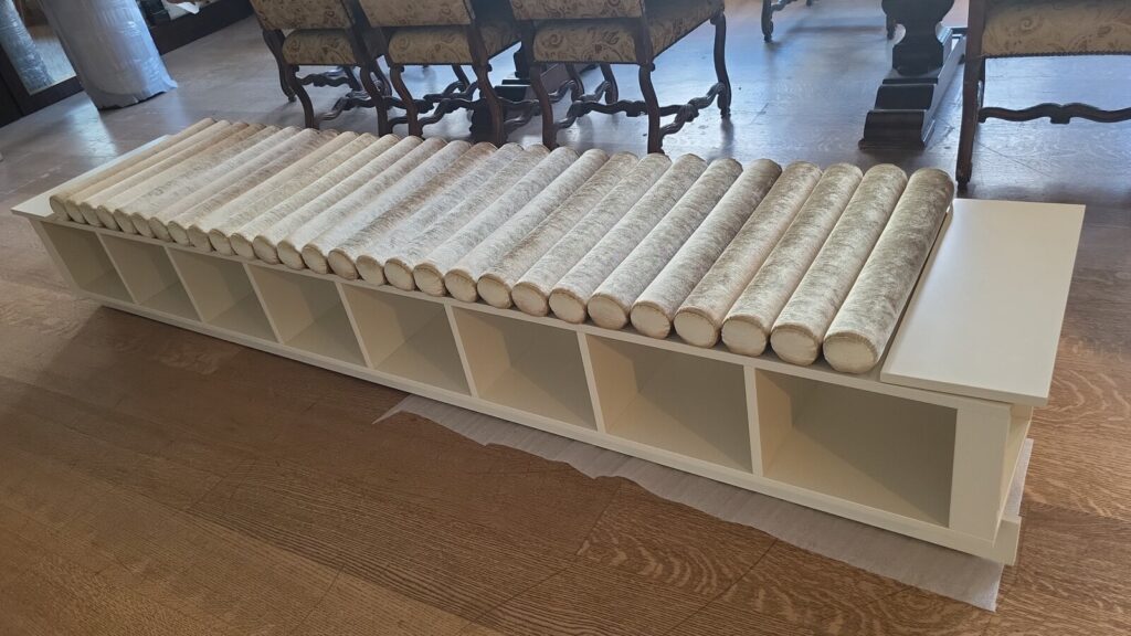 Custom window-seat banquette with foam installed and roll cushions in progress.