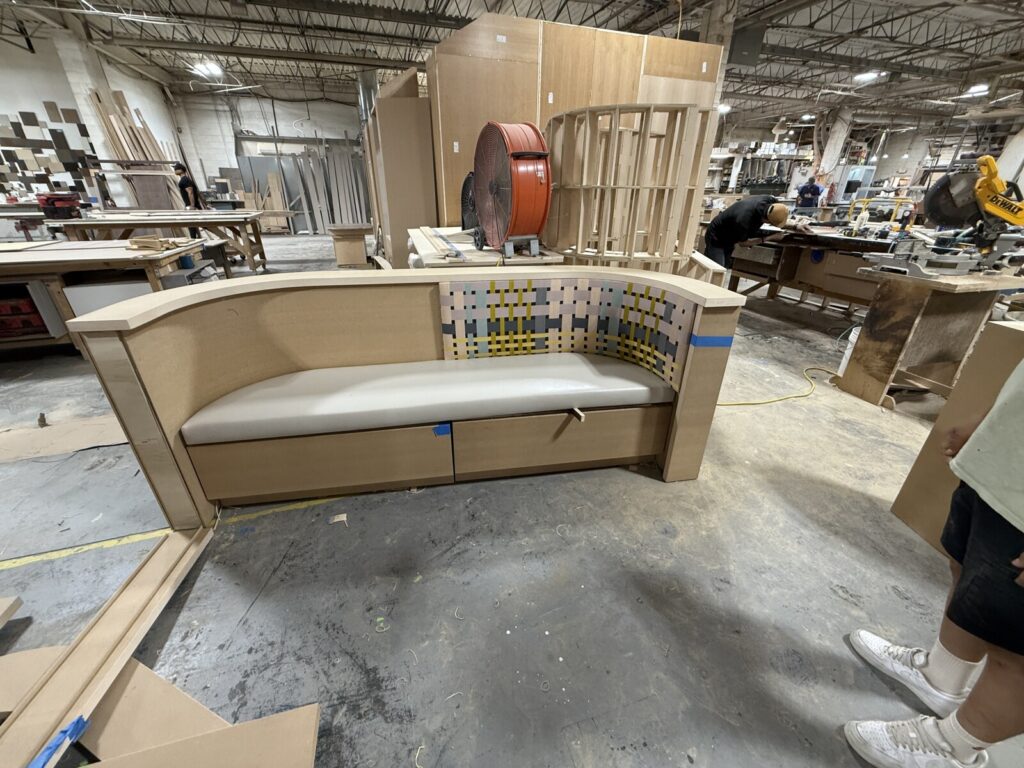 High-back banquette frame in bare wood with vertical supports.