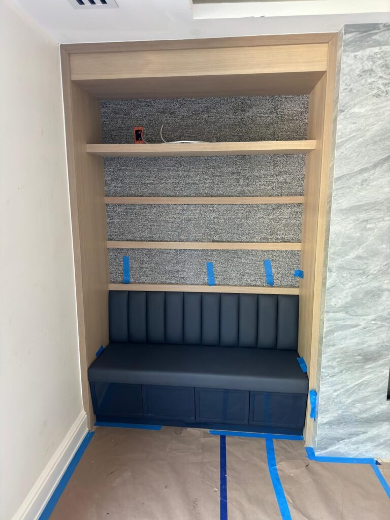Reading nook banquette with dark blue channel‑tufted upholstery and built‑in shelves.