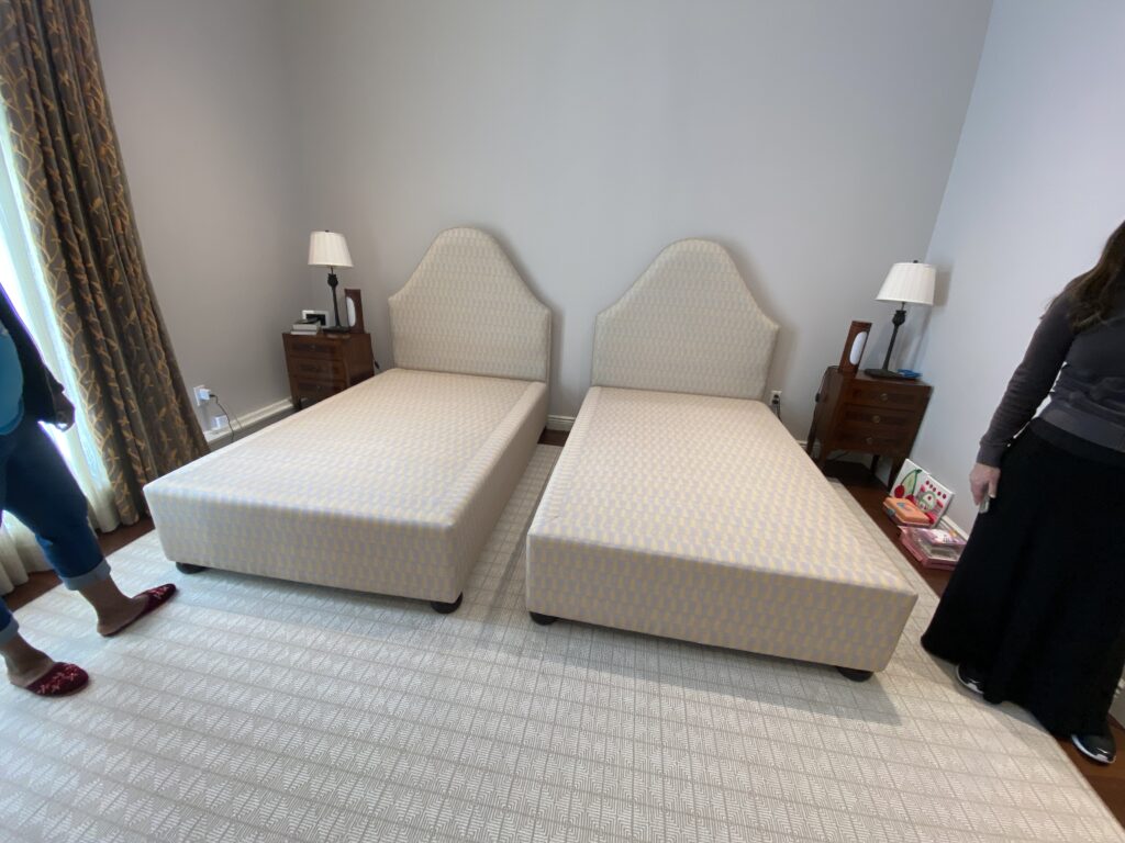 Twin custom bed frames with arched upholstered headboards installed in a client’s bright, completed room.