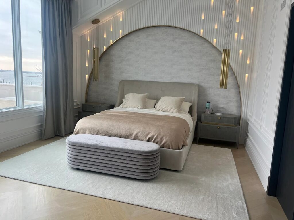 Luxury bedroom with a custom bed, arched upholstered wall feature, and pendant lighting.
