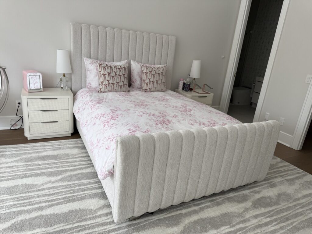 Custom beige vertical channel-tufted platform bed and headboard against a modern bed table.