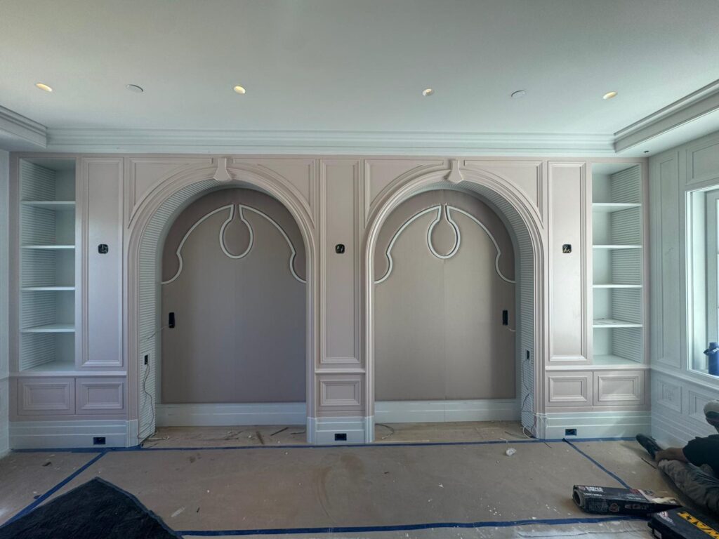 Custom pink millwork with ornate arched fabric wall panel inserts featuring decorative white piping.
