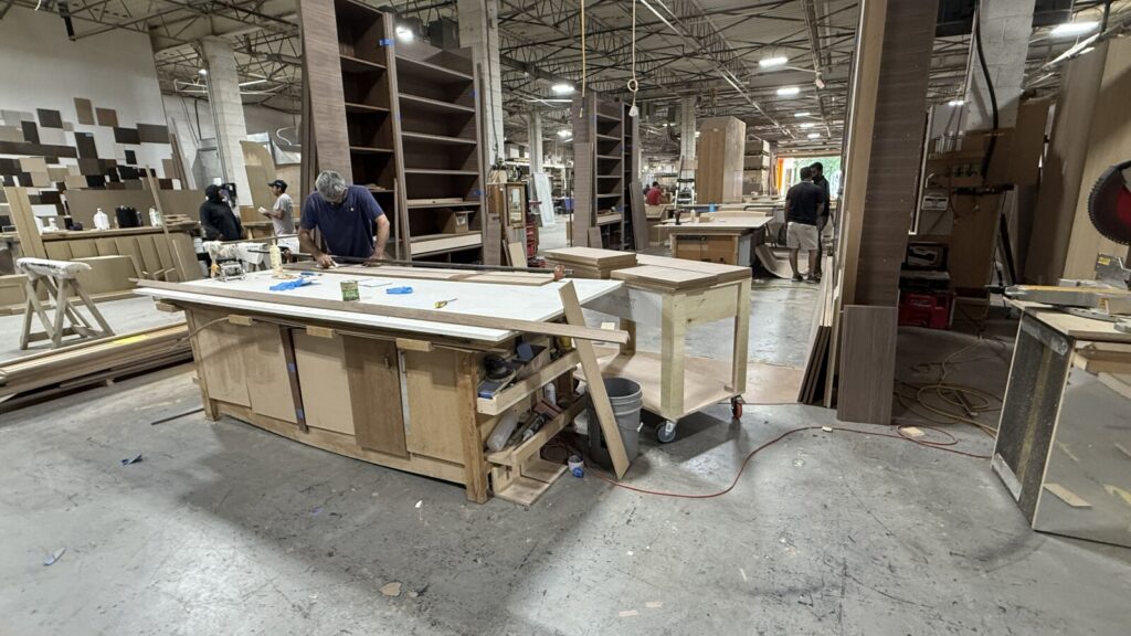 Professional craftsmen assembling large-scale custom furniture and cabinetry in a modern woodworking shop.