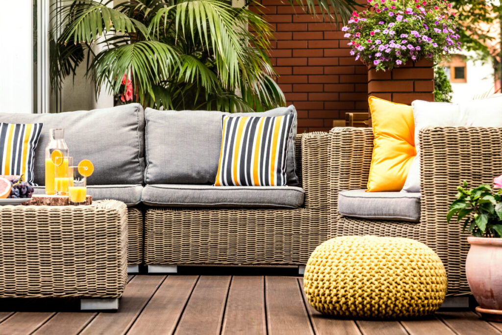 Wicker outdoor sectional with gray cushions and yellow accent pillows on a patio