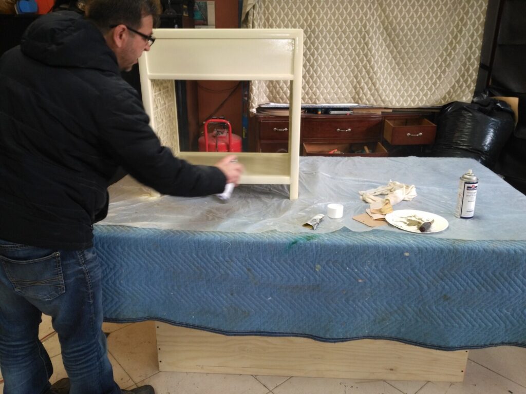 Pair of Baker nightstands in the spray room receiving an even lacquer finish during restoration.